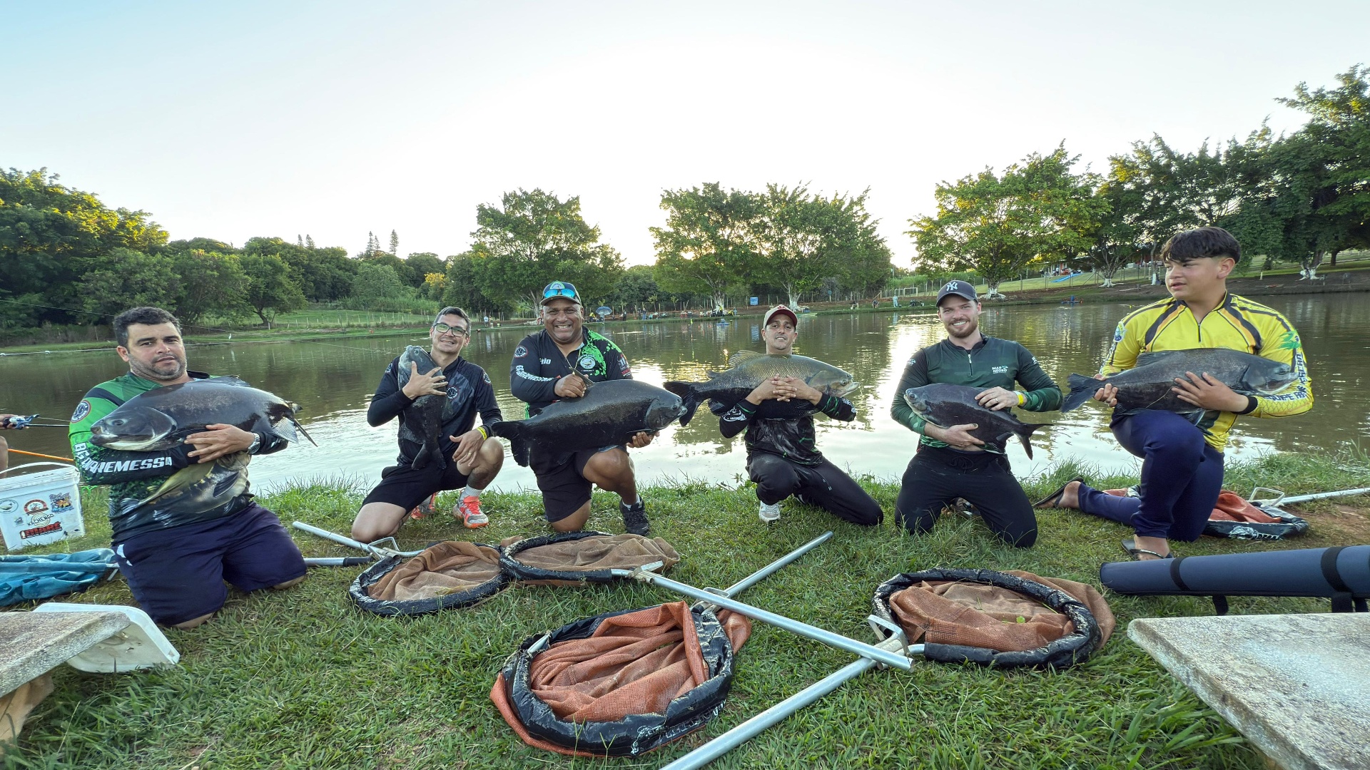 Grupo de amigos com peixes fisgados no lago